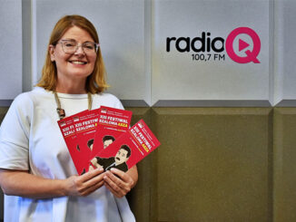 dyrektor Magdalena Konczarek w studiu radia Q, trzyma ulotki trzynastej edycji festiwalu Szaloma Asza